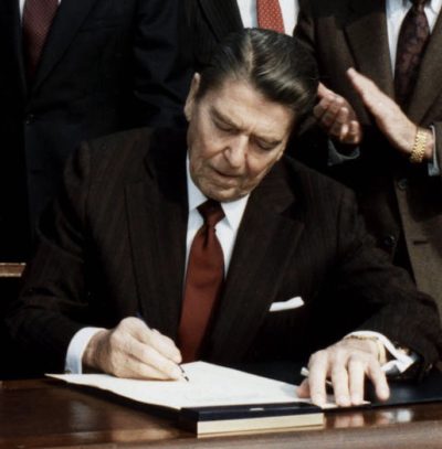 Reagan seated at desk signing bill into law